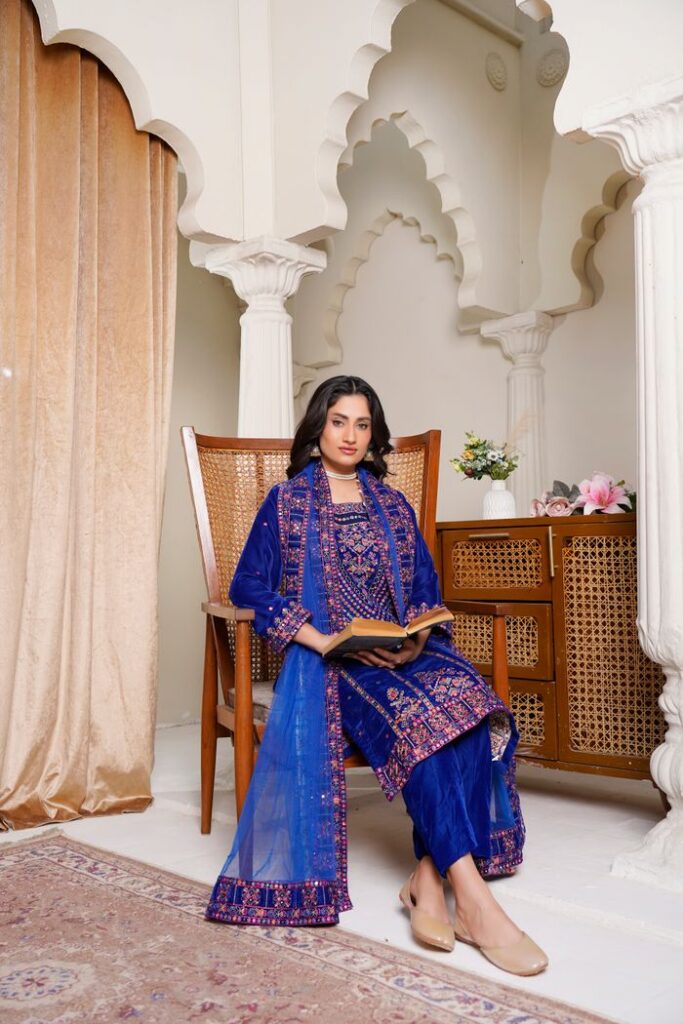 A model in blue traditional attire posing in an ornate Lahore interior.