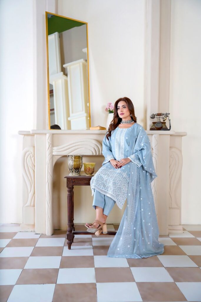 Model in traditional Pakistani dress posing indoors with elegant decor.